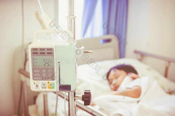 亚洲男孩躺在病床上，用输液泵静脉输液
