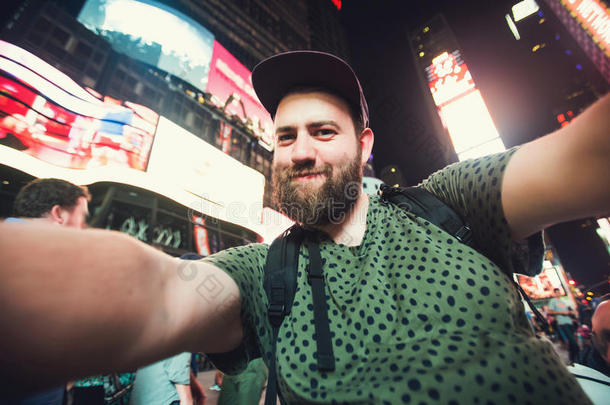有趣的胡须男子背包客微笑和自拍照片在纽约时代广场，而旅行跨越美国