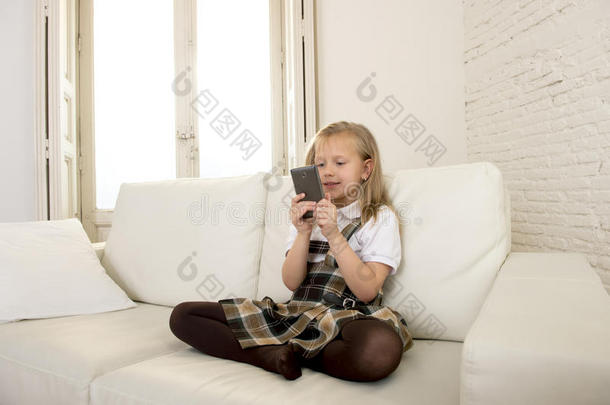 女孩子金发坐在沙发上，使用手机上的互联网应用程序