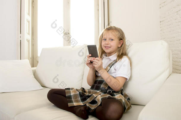 女孩子金发坐在沙发上，使用手机上的互联网应用程序