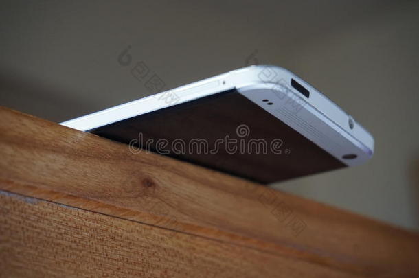 铝电话平衡在木桌的边缘作为一个稳定的概念