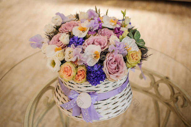 美丽的紫色花束在桌子上的篮子里