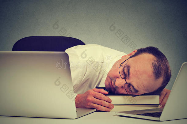 商人用笔记本电脑睡在他的桌子上，疲惫的中年男人雇员