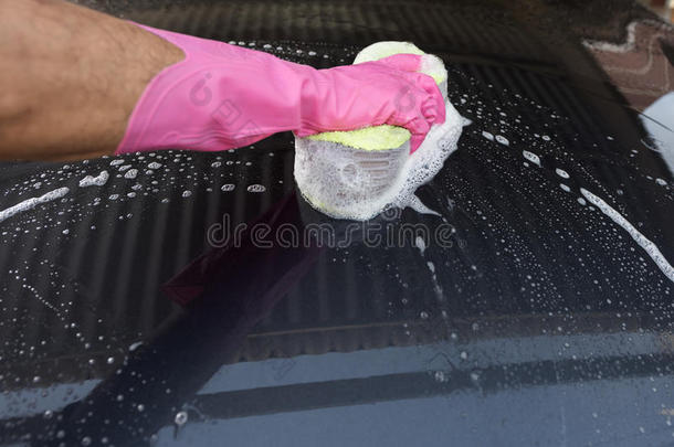 手拿海绵放在车上洗车