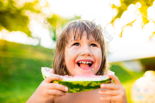 可爱的小女孩在阳光明媚的夏天花园里吃西瓜