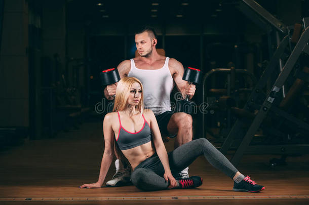 漂亮的年轻运动夫妇展示肌肉和健身哑铃