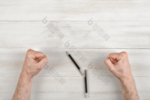 特写男子气概的拳头紧握在木板上，用断了的钢笔