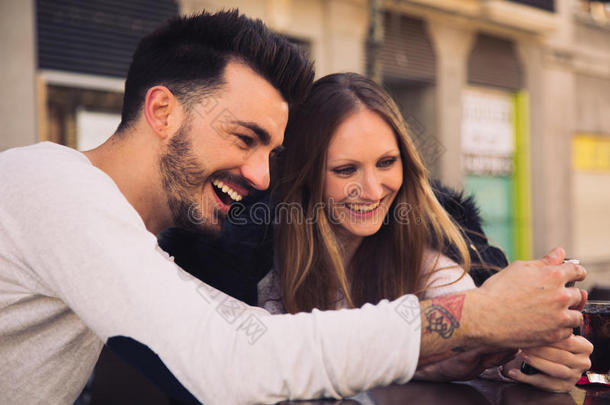一对夫妇使用数字手机iPhone，在露台上大笑