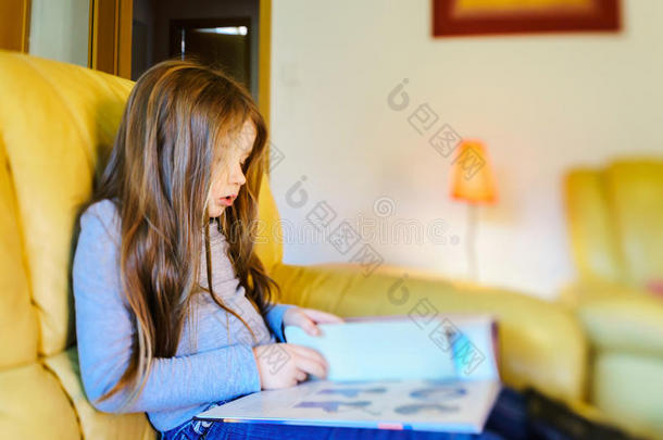 可爱的小女孩，留着长发，在生活中阅读儿童书籍