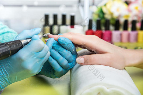 一位在<strong>美甲</strong>沙龙接受指甲锉美容师修剪指甲的妇女的特写镜头。 去修指甲的女人