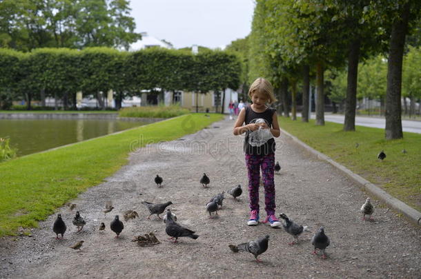 一个女孩正在公园里<strong>喂鸽子</strong>。