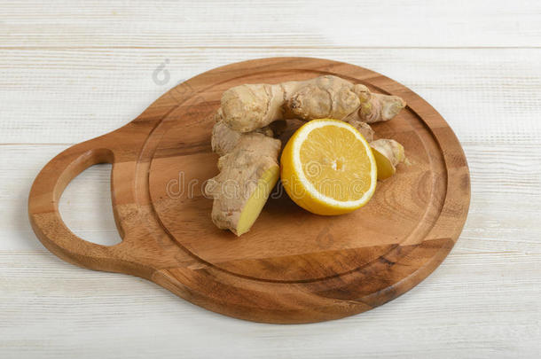 黄色柠檬一半和生姜的组合放置在木制切割板上。 感冒的配料。