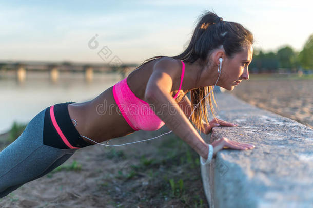 健身妇女做俯卧撑户外训练锻炼夏季晚上。 概念运动健康的生活方式。