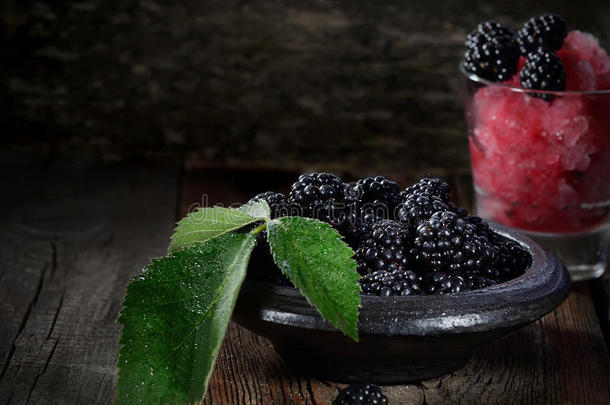 芬芳成熟的黑莓在一个盘子里，水果冰在一个黑暗的木制背景上