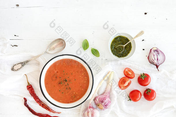 在乡村金属碗中加入新鲜西红柿、绿色酱汁、辣椒、大蒜和罗勒的凉拌菜汤