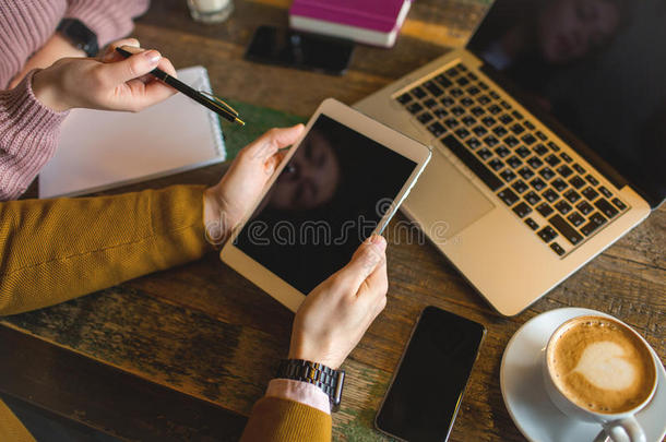 在时髦的咖啡馆里拿着笔记本电脑智能手机平板电脑和咖啡