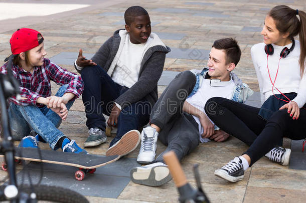 女孩和三个男孩在户外闲逛，讨论一些事情