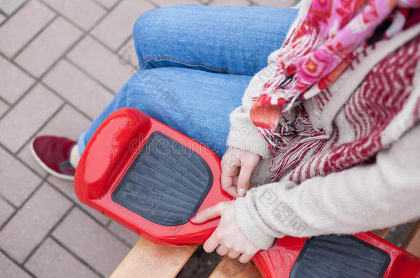 女孩持有现代红色电动迷你Segway或悬停板滑板车