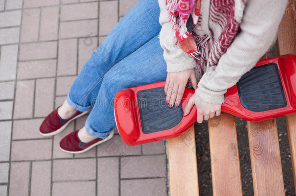 女孩持有现代红色电动迷你Segway或悬停板滑板车