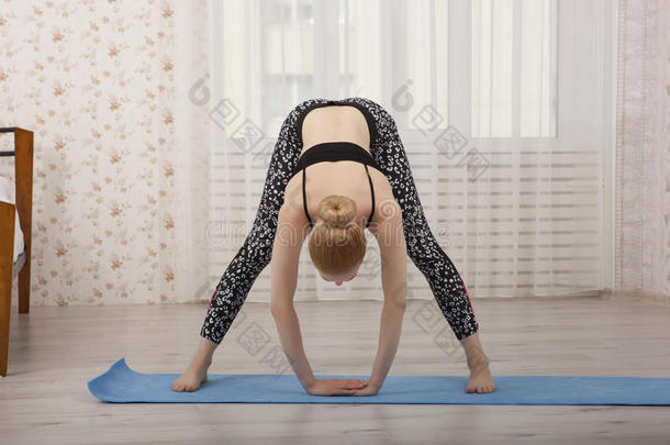 美丽的年轻女人在<strong>垫子</strong>上在家练习瑜伽伸展
