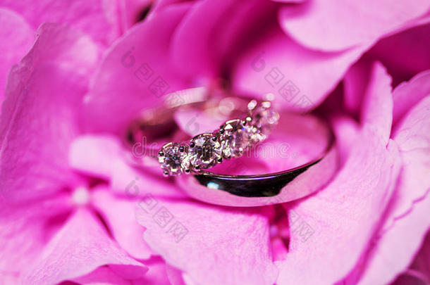 金色的结婚戒指上有钻石，粉红色的花