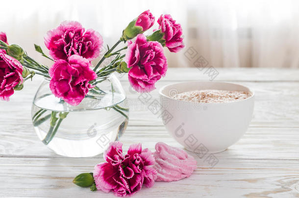 卡布奇诺和自制棉花糖甜点，木制桌子上的粉红色康乃馨