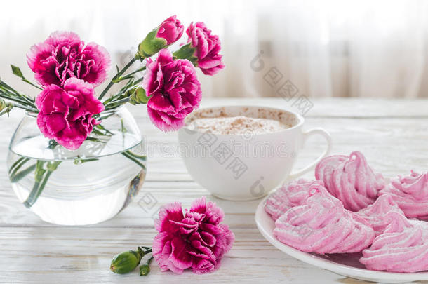 卡布奇诺和自制棉花糖甜点，木制桌子上的粉红色康乃馨