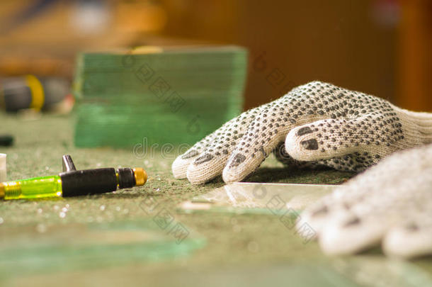 特写手戴白色工作手套，手持切割雕刻工具，玻璃躺在前面