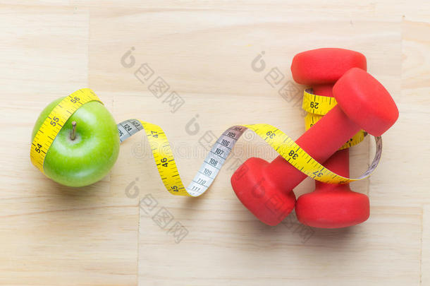 新鲜绿色苹果、测量带和哑铃减肥的概念。 健身饮食方案。 顶部视角与副本