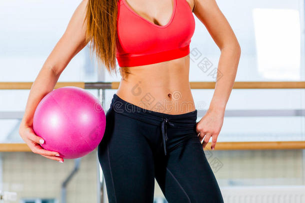 一个年轻女孩漂亮的运动腰部，手里拿着粉红色的球