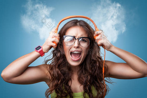 愤怒的紧张女孩戴着耳机听音乐