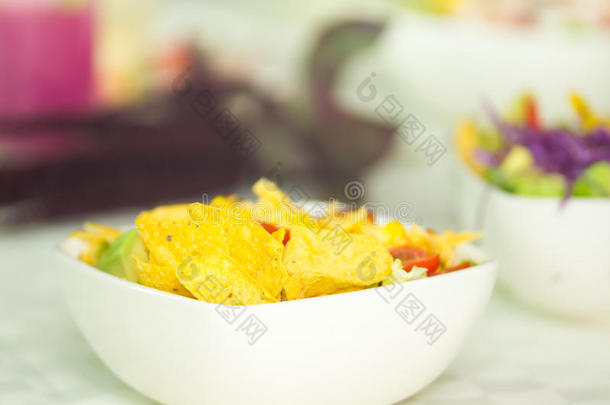 特写墨西哥沙拉在白色碗，黄色玉米饼薯片和西红柿可见