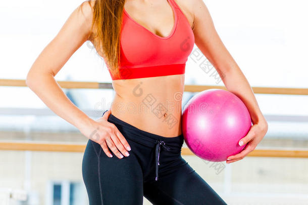 一个年轻女孩漂亮的<strong>运动腰部</strong>，手里拿着粉红色的球