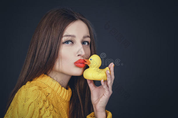 黑发女人，红唇亲吻黄色橡胶鸭子