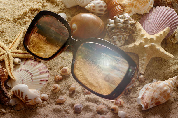 沙子上有不同<strong>的</strong>贝壳和太阳镜。 夏天<strong>的</strong>海滩背景。 假期<strong>海报的</strong>概念