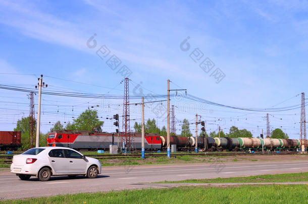 铁路上的货运列车和汽车在绿色草地附近的道路上行驶