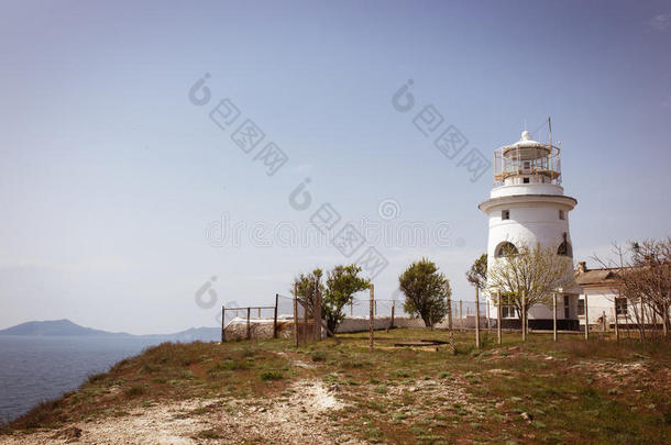 美丽的白色灯塔在海上海岸线上。 夏天的海景。