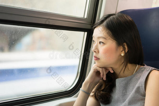 美丽的亚洲女人看着火车窗外，有复制空间