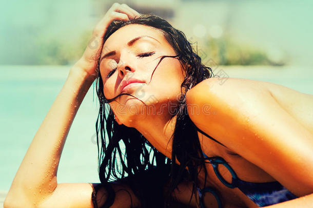 游泳池旁边的漂亮女人晒太阳