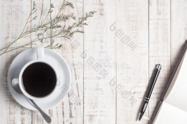 木桌背景上的一杯热咖啡和白色便签本