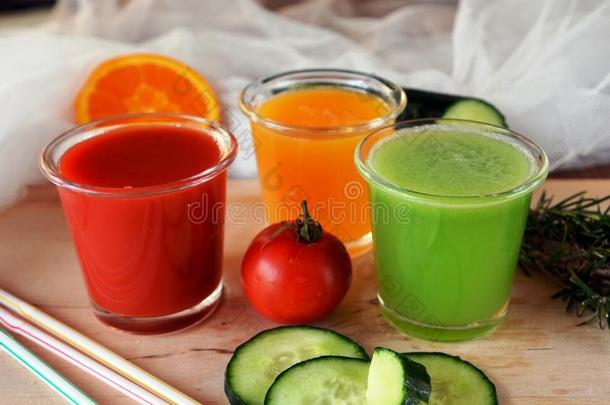 新鲜的橘子，西红柿和黄瓜冰沙在玻璃杯上。