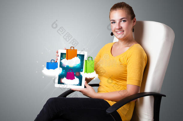 手持现代平板<strong>电脑</strong>的女人在云<strong>端</strong>挂着五颜六色的购物袋