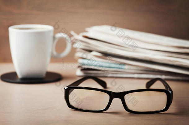 眼镜，咖啡杯和一叠报纸在木制桌子上，<strong>主题</strong>是眼科，视力和<strong>阅读</strong>差