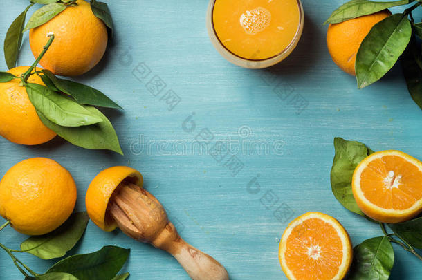新鲜橙汁在玻璃和橘子与树叶在木制绿松石蓝色油漆背景