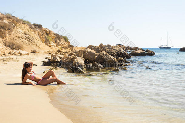 女孩躺在海滩上，日光浴和放松。 夏季出海之旅。