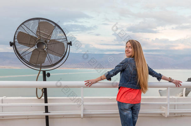 金发女郎年轻的女人摆出阳台<strong>呼吸机</strong>海景。