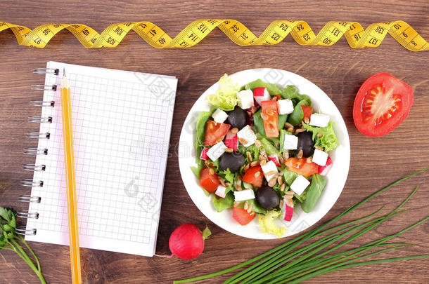 新鲜希腊沙拉配蔬菜，厘米和记事本写笔记，健康营养和减肥概念