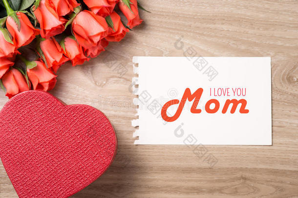 一束新鲜的粉红色红玫瑰，木背景上有礼物。 花卉浪漫安排与卡片文本快乐母亲节