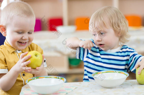 有趣的微笑孩子在幼儿园吃苹果