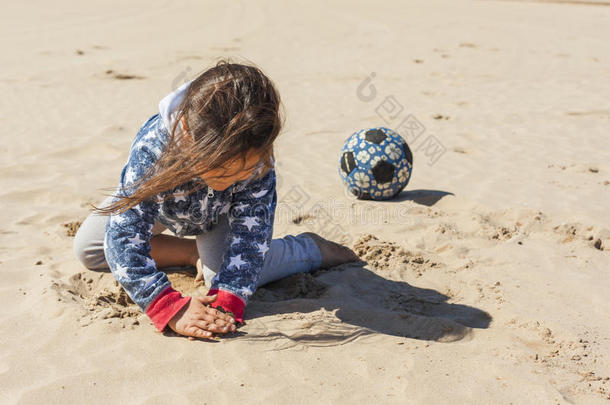 在复活节的一个刮风的日子里，女孩在海滩上玩沙子